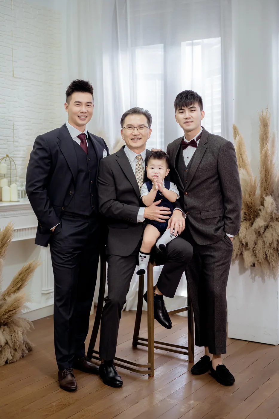 Three men in suits, the eldest seated with a baby on his lap
