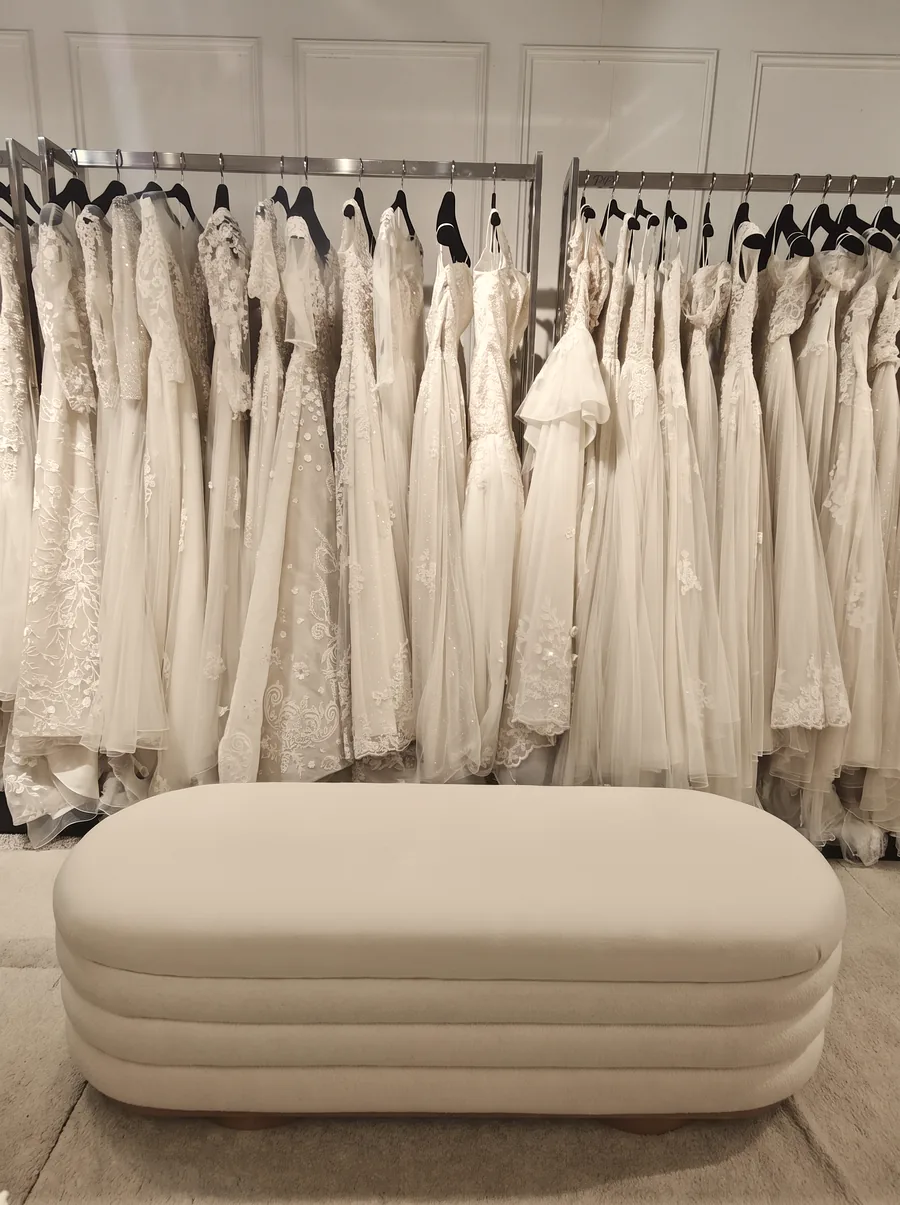 Lace and tulle gowns on the boutique rail behind the fitting bench